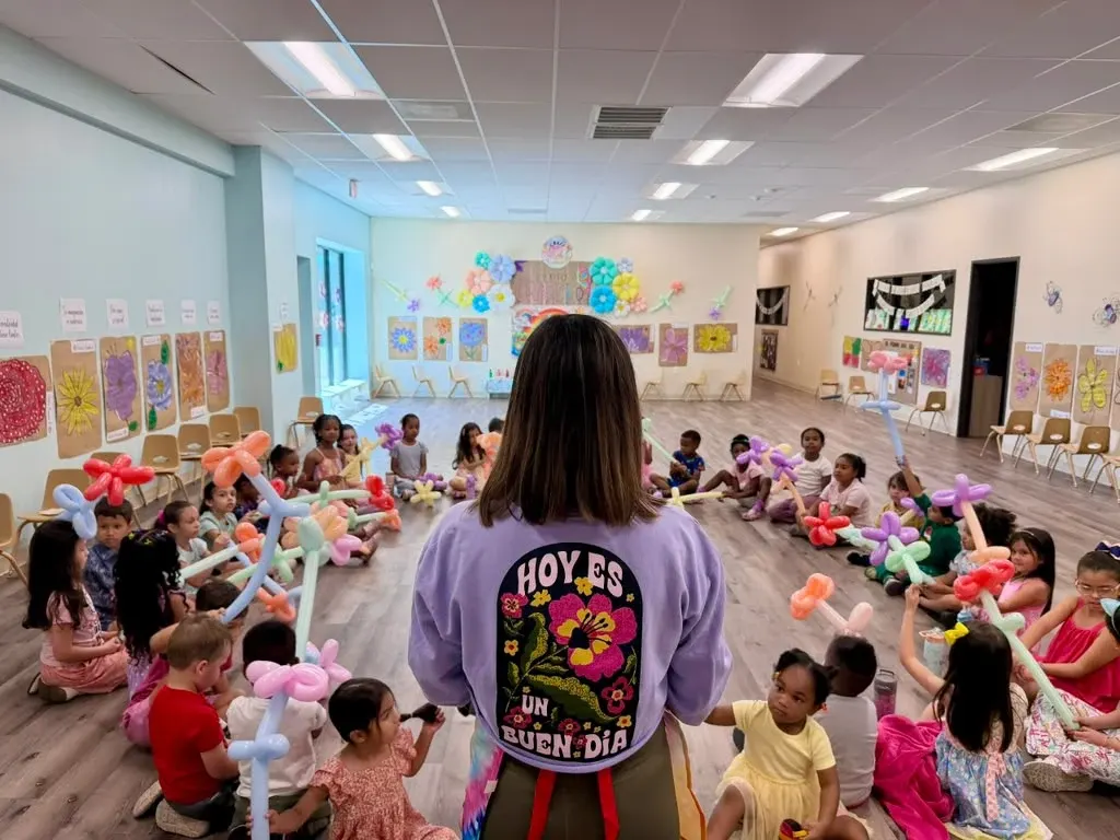 Ms. Rebeca dirigiendo una actividad con globos ante un grupo de niños